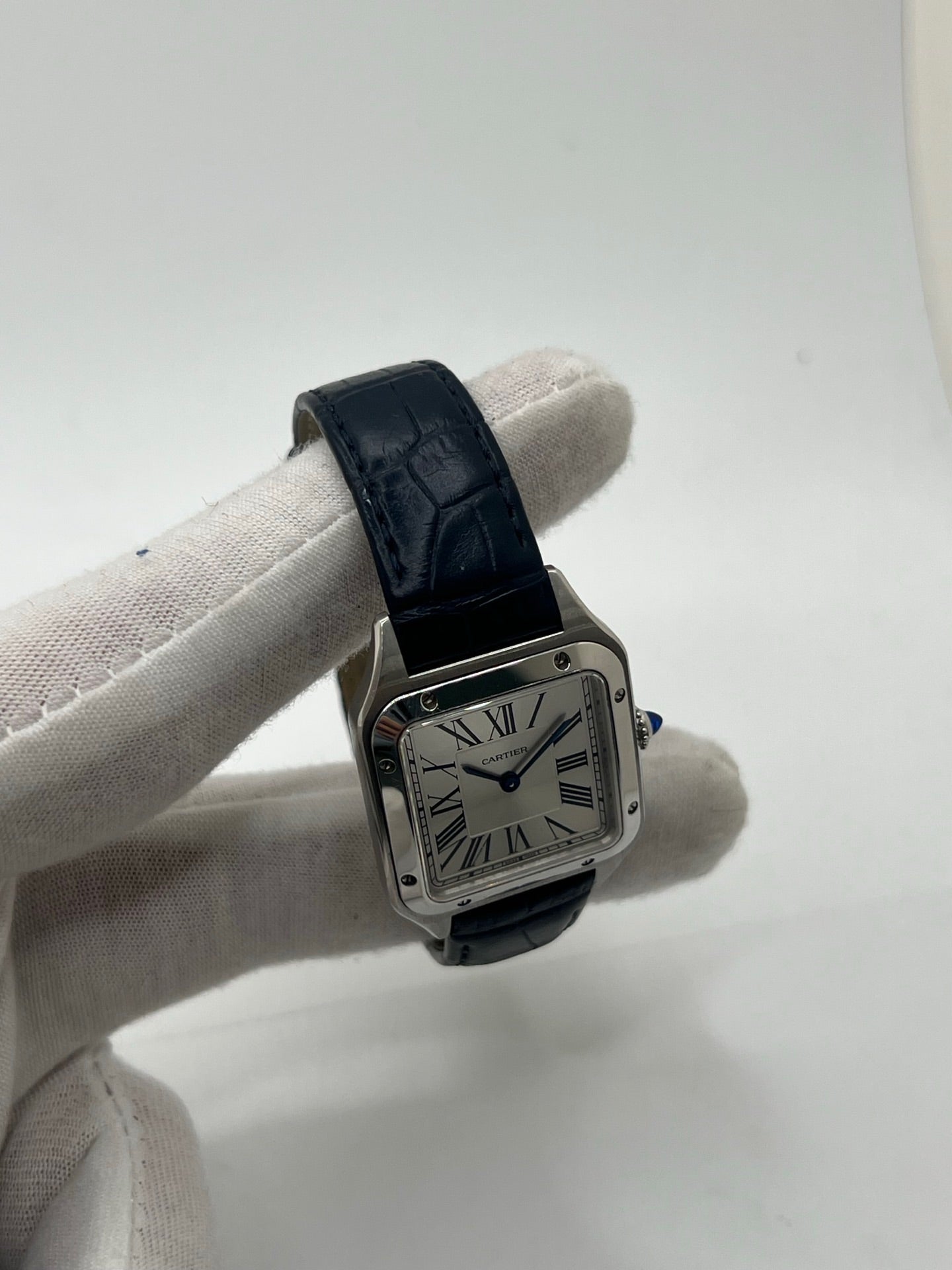 Montre élégante Santos Dumont en acier avec cadran argent et chiffres romains, équipée d’un mouvement quartz précis. Bracelet en cuir de crocodile bleu avec boucle ardillon en acier. Boîtier 38 x 27,5 mm, verre saphir et étanchéité 3 ATM. Design raffiné, idéal pour un style classique et sophistiqué. Disponible avec coffret et papiers d’origine.