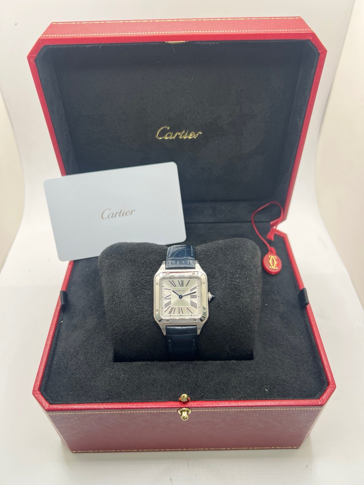 Montre élégante Santos Dumont en acier avec cadran argent et chiffres romains, équipée d’un mouvement quartz précis. Bracelet en cuir de crocodile bleu avec boucle ardillon en acier. Boîtier 38 x 27,5 mm, verre saphir et étanchéité 3 ATM. Design raffiné, idéal pour un style classique et sophistiqué. Disponible avec coffret et papiers d’origine.