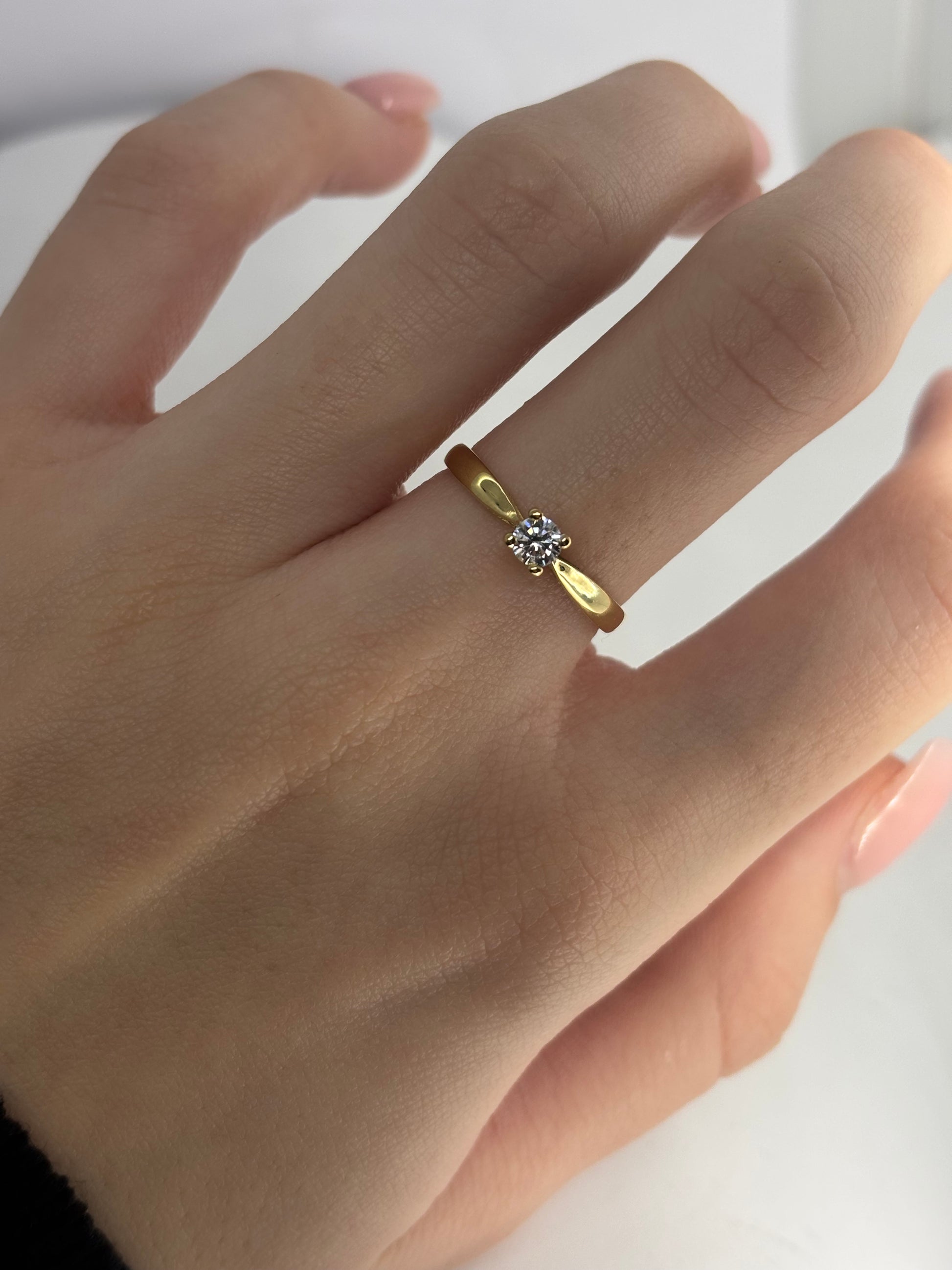 Solitaire en or jaune 18 carats serti d’un diamant taille brillant de 0,18 carat. Son design épuré et élégant met en valeur l’éclat naturel de la pierre ainsi que la chaleur lumineuse de l’or jaune. Intemporelle et raffinée, cette bague se porte aussi bien pour un engagement que comme bijou symbolique au quotidien, alliant simplicité et sophistication.