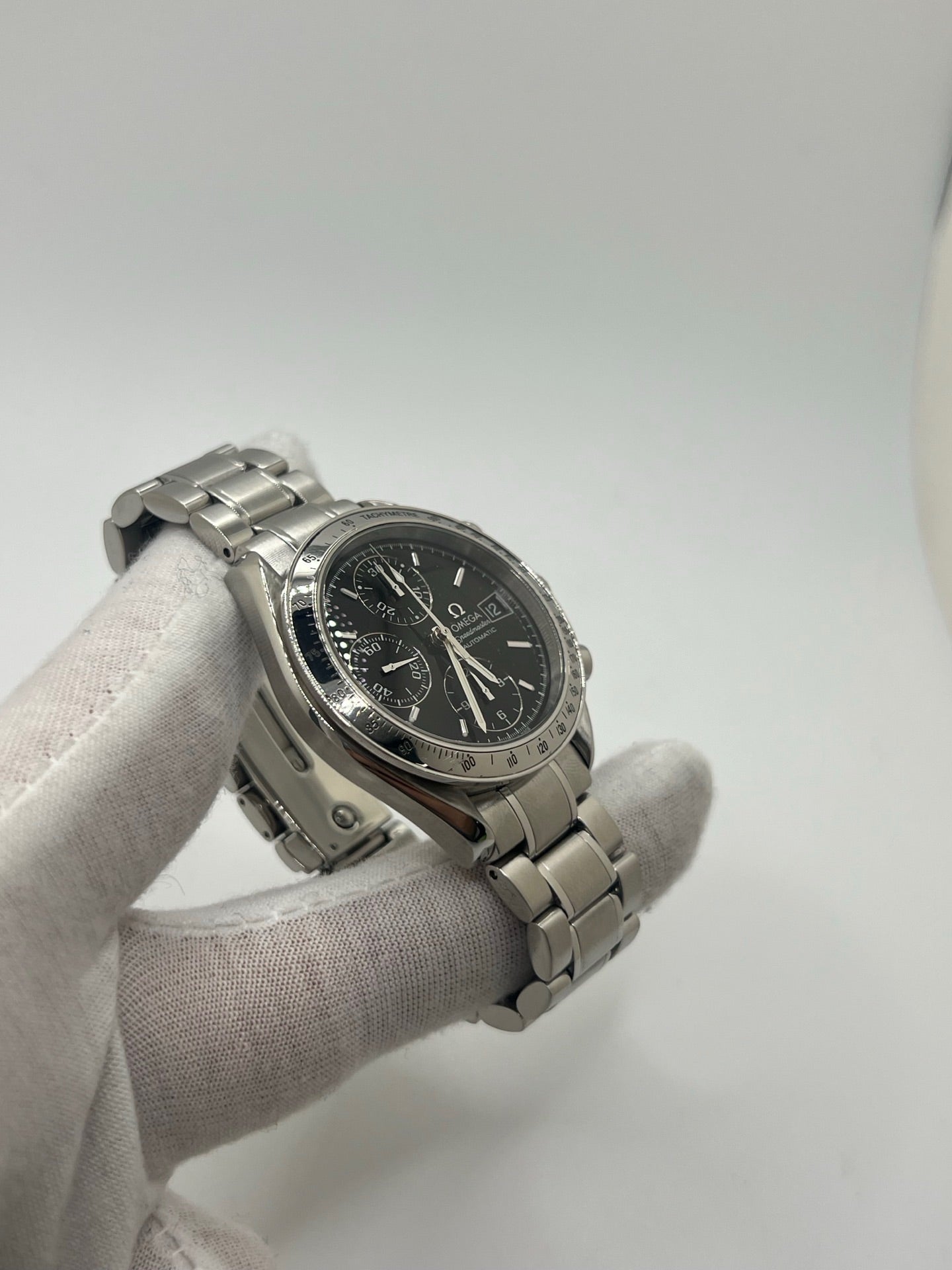 Montre Omega Speedmaster Date référence 3513.50 en acier, chronographe automatique avec boîtier de 39 mm et bracelet en acier assorti. Cadran noir sobre sans chiffres, protégé par un verre saphir, avec affichage de la date et fonctions chronographe. Modèle étanche 5 ATM, animé par le calibre automatique 1152 offrant 44 heures de réserve de marche. Montre homme élégante et sportive, emblématique de la collection Speedmaster.