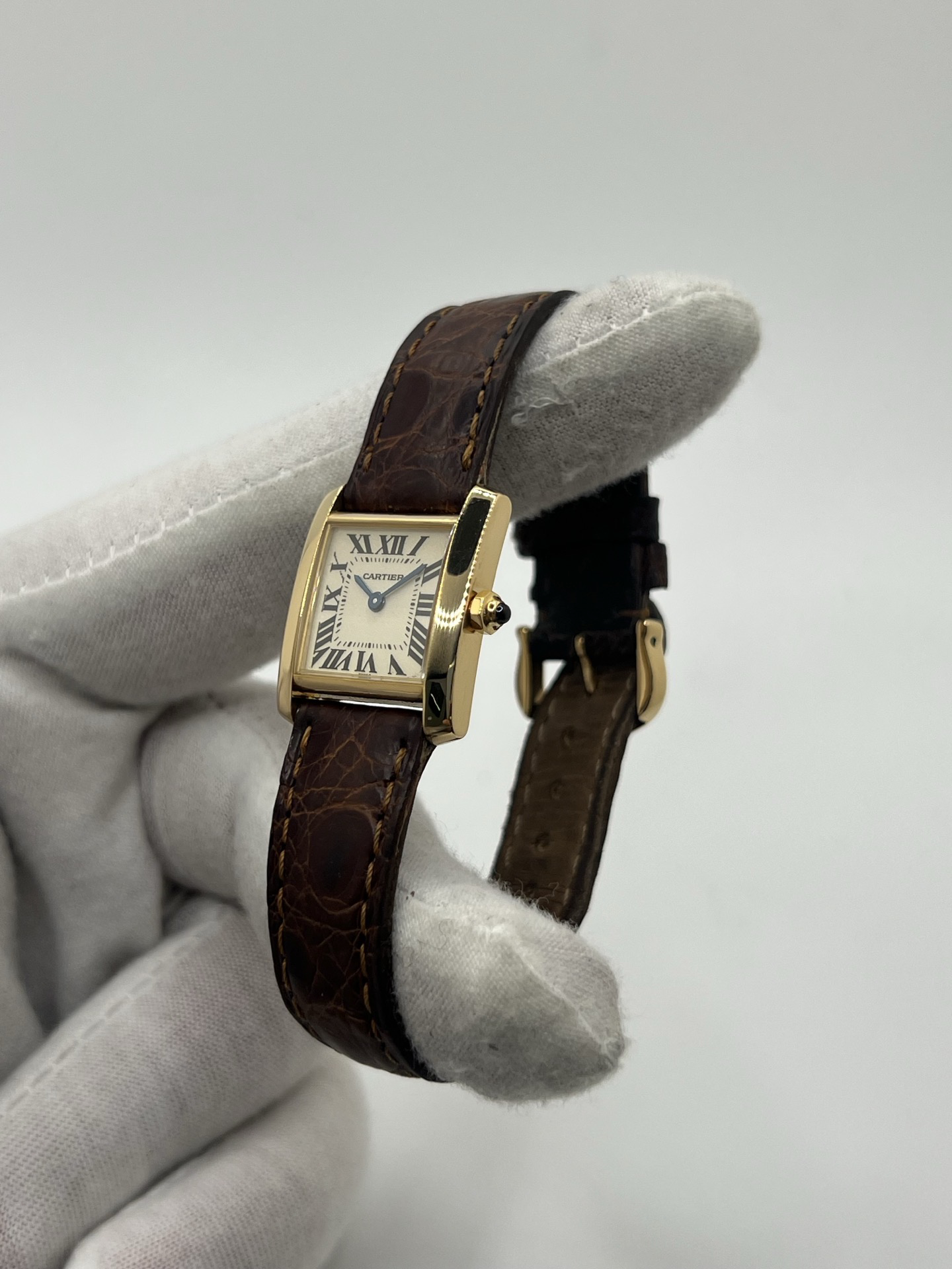 Montre Cartier Tank Française référence 1820 en or jaune 18K, petit modèle pour femme, boîtier rectangulaire emblématique aux lignes droites et élégantes, cadran blanc avec chiffres romains noirs, minuterie chemin de fer et aiguilles bleuies en forme de glaive. Bracelet intégré en acier avec boucle déployante. Mouvement quartz précis. Montre de luxe intemporelle, raffinée et iconique, idéale pour un porté quotidien ou une tenue habillée.