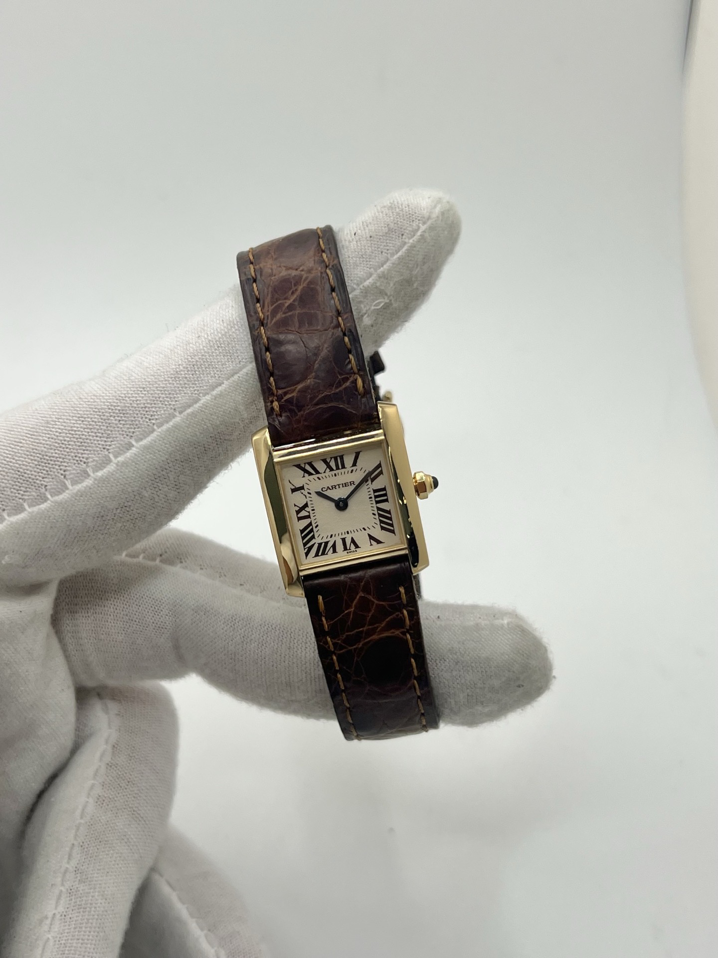 Montre Cartier Tank Française référence 1820 en or jaune 18K, petit modèle pour femme, boîtier rectangulaire emblématique aux lignes droites et élégantes, cadran blanc avec chiffres romains noirs, minuterie chemin de fer et aiguilles bleuies en forme de glaive. Bracelet intégré en acier avec boucle déployante. Mouvement quartz précis. Montre de luxe intemporelle, raffinée et iconique, idéale pour un porté quotidien ou une tenue habillée.