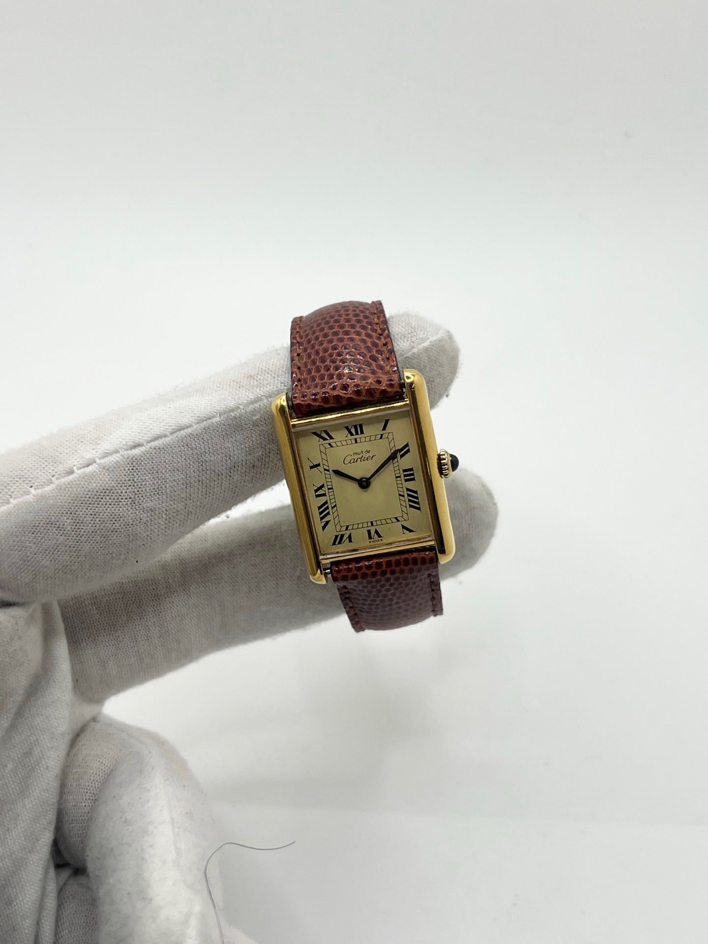 Montre Cartier Tank Must Vermeil, boîtier argent 31 x 23 mm, mouvement à remontage manuel Cartier 78-1 avec réserve de marche de 44 h et 17 pierres. Cadran blanc à chiffres romains, verre minéral. Bracelet en cuir de lézard brun avec boucle en argent. État d’occasion très bon avec légères rayures, alliant élégance intemporelle et design iconique pour homme ou unisexe.