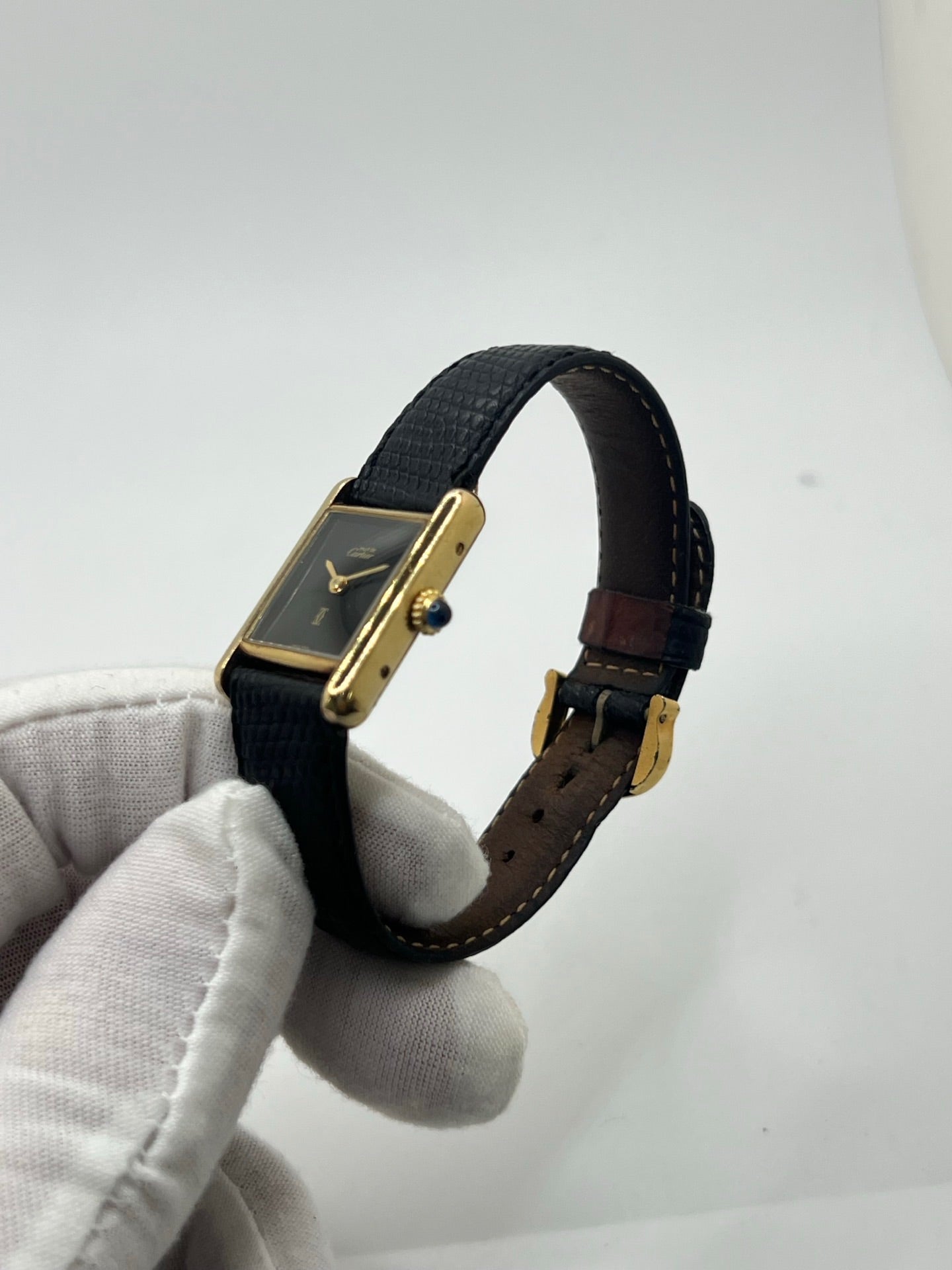 Montre Cartier Tank Must Vermeil référence 5057001 pour femme, boîtier en argent 20 x 28 mm, cadran noir sans chiffres et bracelet en cuir de lézard noir. Modèle à mouvement quartz, en bon état avec traces d’usure légères. Montre élégante au style intemporel, idéale pour un look sophistiqué et raffiné. Parfaite pour les amateurs de pièces vintage.