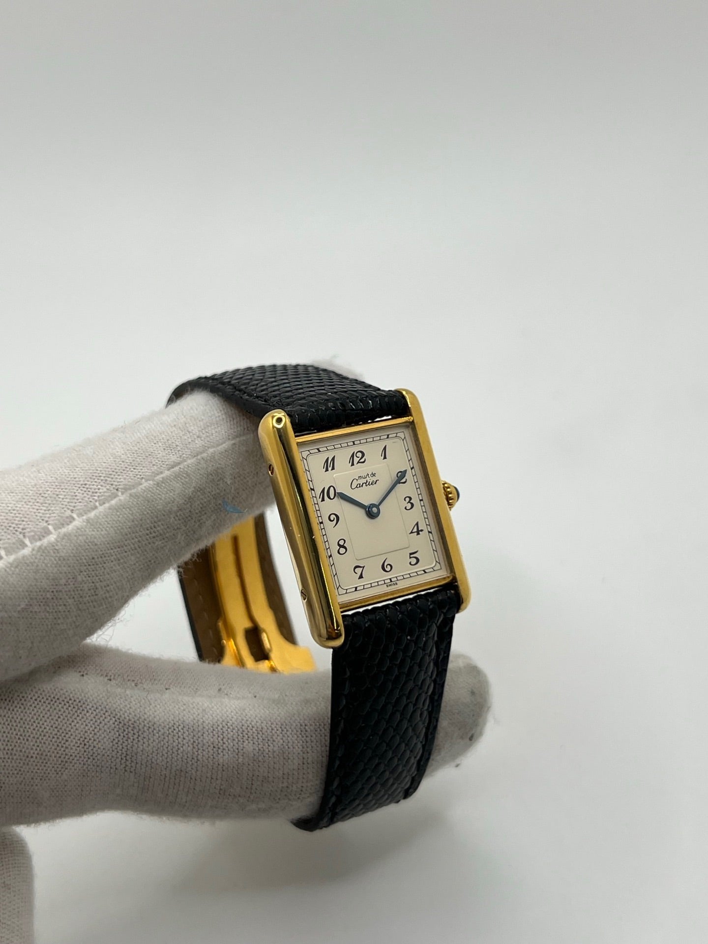 Montre Cartier Tank Vermeil référence 590005 vintage de 1989, avec boîtier rectangulaire en argent aux proportions classiques 23 x 30 mm, cadran argenté élégant avec chiffres arabes noirs et aiguilles bleuies, verre saphir et mouvement quartz. Montée sur un bracelet en cuir de lézard noir avec boucle ardillon en acier. Modèle iconique au design intemporel, livré avec son coffret et ses papiers d’origine, en très bon état.