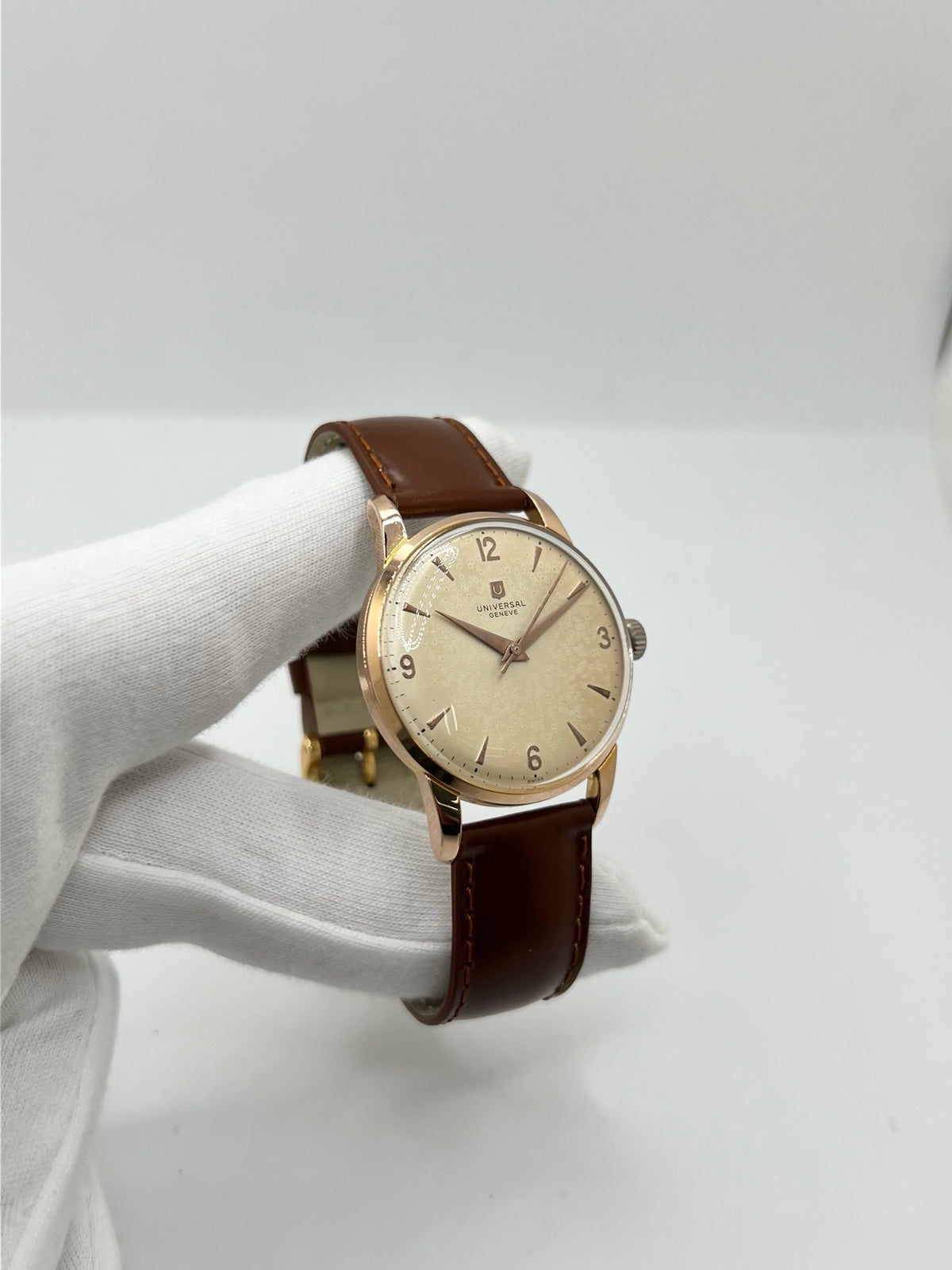Montre Universal Genève 412501/1 vintage en très bon état, datant approximativement de 1950, avec un mouvement à remontage manuel. Son boîtier de 34,5 mm plaqué or est associé à un cadran blanc à chiffres arabes et un verre Plexiglas. Cette montre Universal Genève possède un bracelet en cuir brun avec boucle ardillon en acier. Un modèle homme ou unisexe au style classique et élégant, idéal pour les amateurs d’horlogerie vintage.