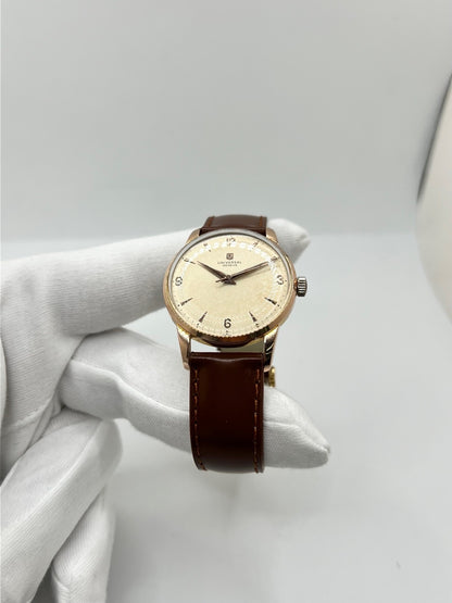 Montre Universal Genève 412501/1 vintage en très bon état, datant approximativement de 1950, avec un mouvement à remontage manuel. Son boîtier de 34,5 mm plaqué or est associé à un cadran blanc à chiffres arabes et un verre Plexiglas. Cette montre Universal Genève possède un bracelet en cuir brun avec boucle ardillon en acier. Un modèle homme ou unisexe au style classique et élégant, idéal pour les amateurs d’horlogerie vintage.