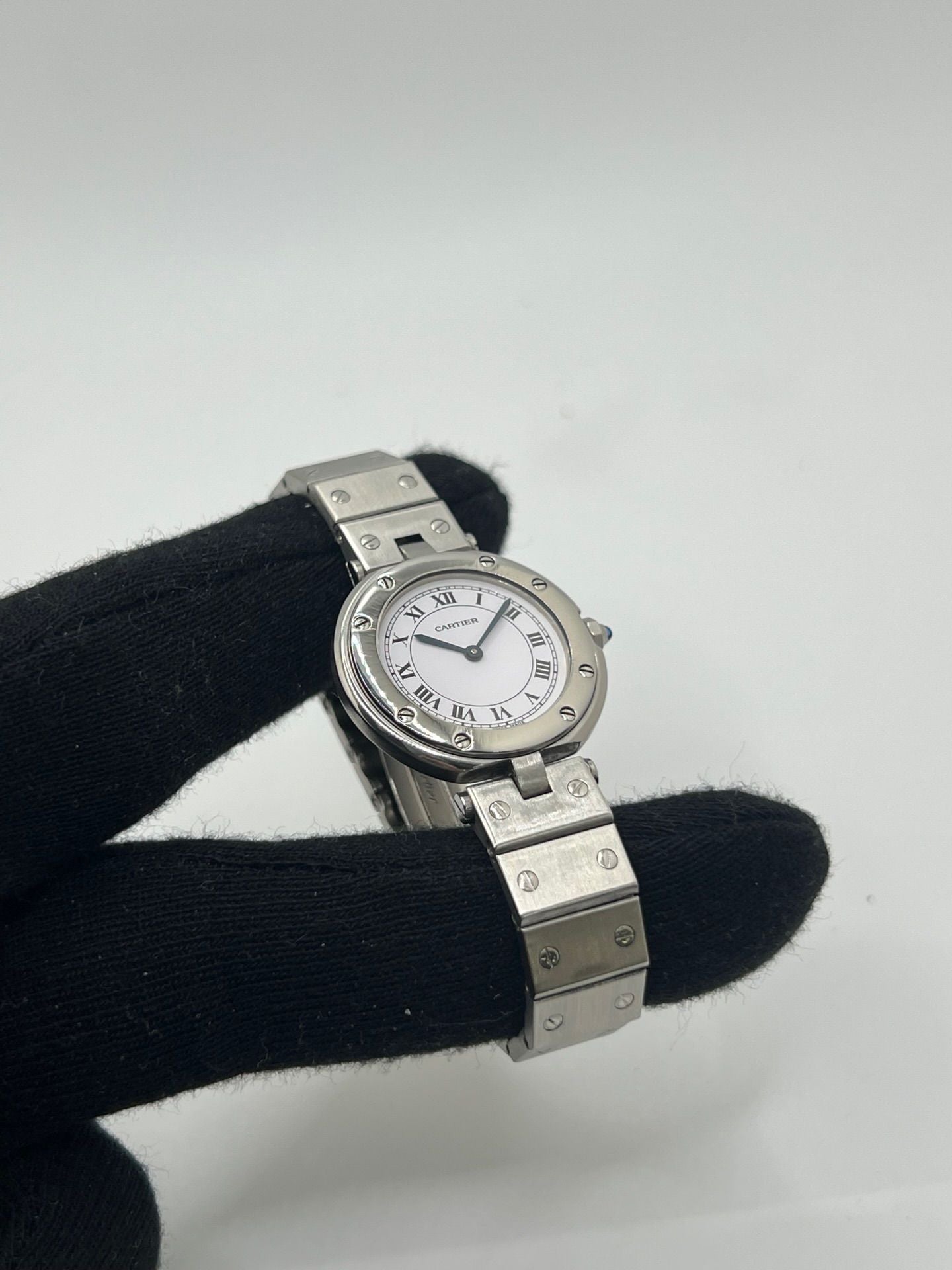 Montre Cartier Santos Vendôme référence 8192 en acier, modèle pour femme avec boîtier rond de 27 mm, cadran blanc à chiffres romains et mouvement quartz. Bracelet acier assorti, boucle à plis et verre saphir. Montre vintage de 1981 en très bon état, livrée avec coffret et papiers d’origine.