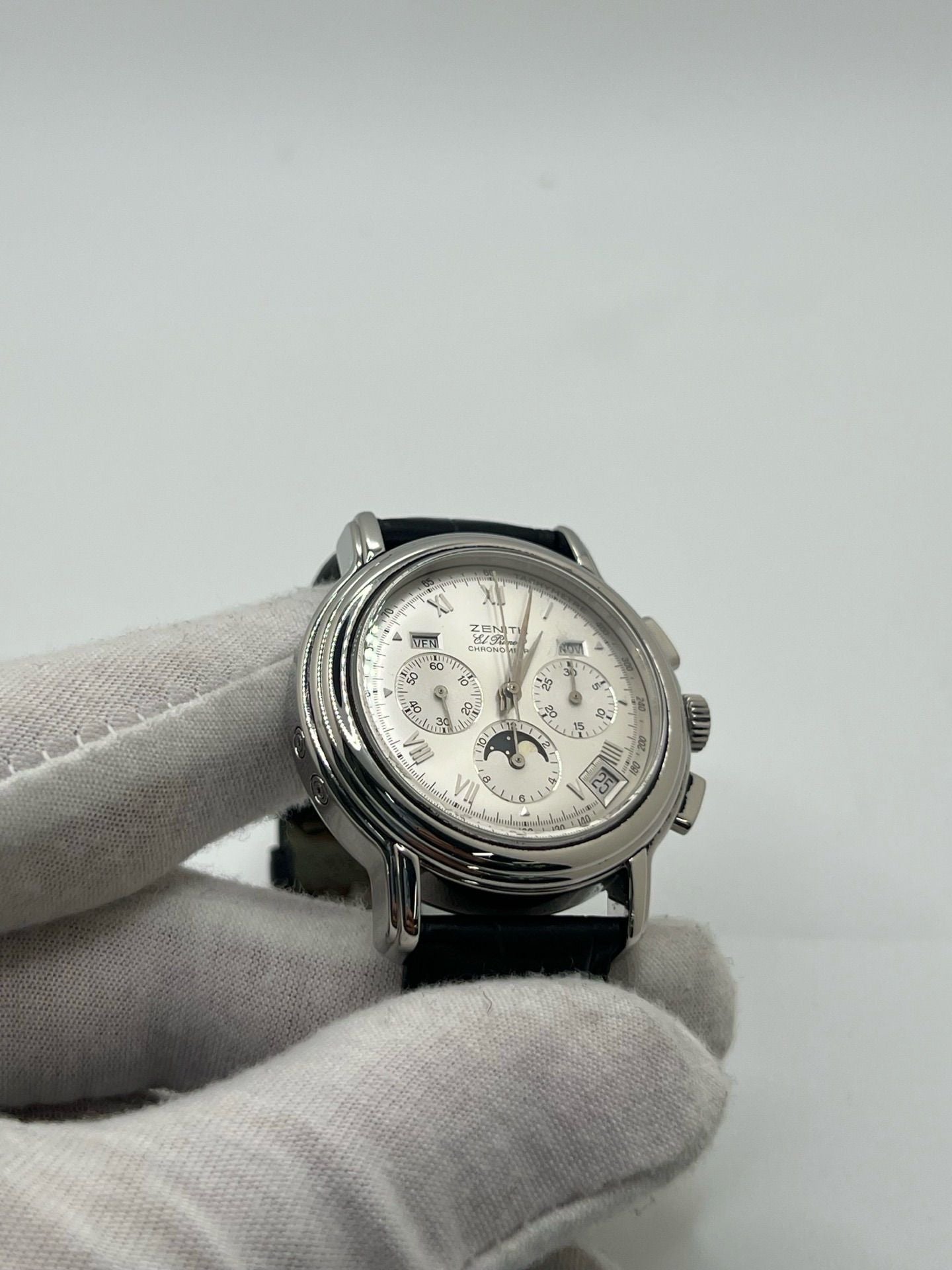 Montre chronographe automatique en acier avec cadran argenté à chiffres romains, fonction phase lunaire, date, jour et mois. Boîtier de 40 mm, verre saphir, fond transparent et bracelet en cuir noir. Modèle de haute précision doté du calibre 410 avec 50 heures de réserve de marche. Montre élégante pour homme ou unisexe.