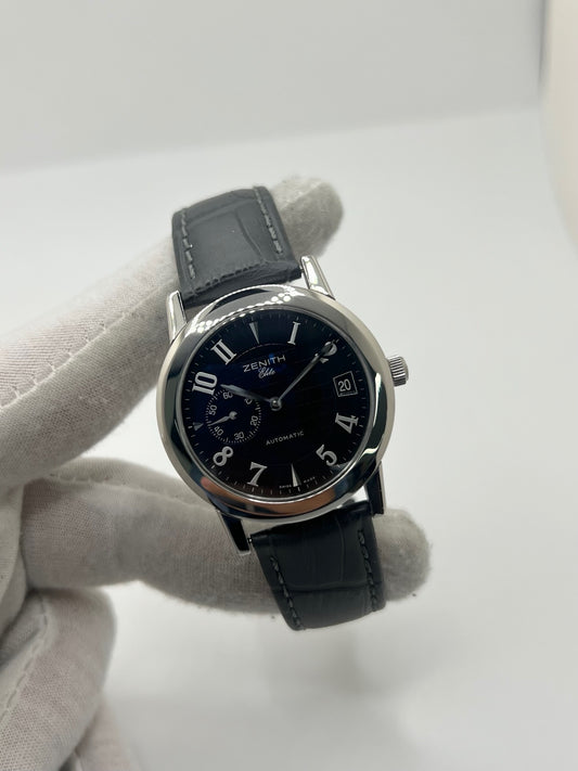 Montre Zenith Port Royal automatique en acier, modèle homme ou unisexe de 2007, équipée d’un boîtier de 37 mm et d’un élégant cadran noir à chiffres arabes. Cette montre d’occasion en très bon état dispose d’un verre saphir, d’une fonction date et d’une petite seconde. Son bracelet en cuir noir avec boucle ardillon souligne son style raffiné. Une montre Zenith Port Royal de luxe au design intemporel, idéale pour les passionnés d’horlogerie et les amateurs de pièces élégantes.