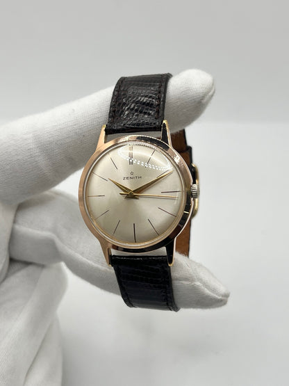 Montre Zenith Stellina vintage à remontage manuel, dotée d’un boîtier plaqué or et d’un élégant cadran champagne. Cette montre Zenith se distingue par son style classique et intemporel, emblématique de l’horlogerie traditionnelle. Elle est équipée d’un bracelet brun en cuir de lézard, complété par une boucle ardillon en acier. Avec son esthétique raffinée et son allure rétro, la Zenith Stellina séduit les amateurs de montres anciennes et de pièces horlogères au charme authentique.